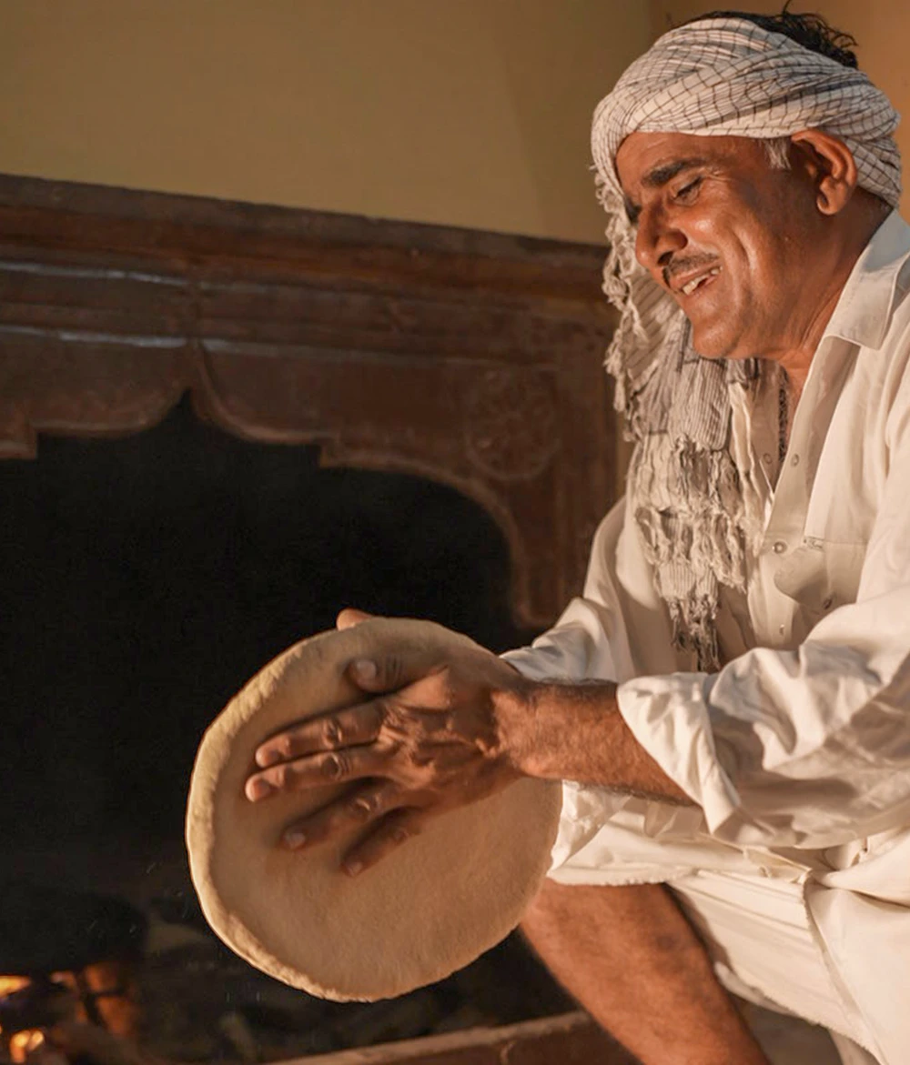 Meer Khan, son of Kuldhara, preparing traditional roti on a live chulha at Dreamtime Bungalows