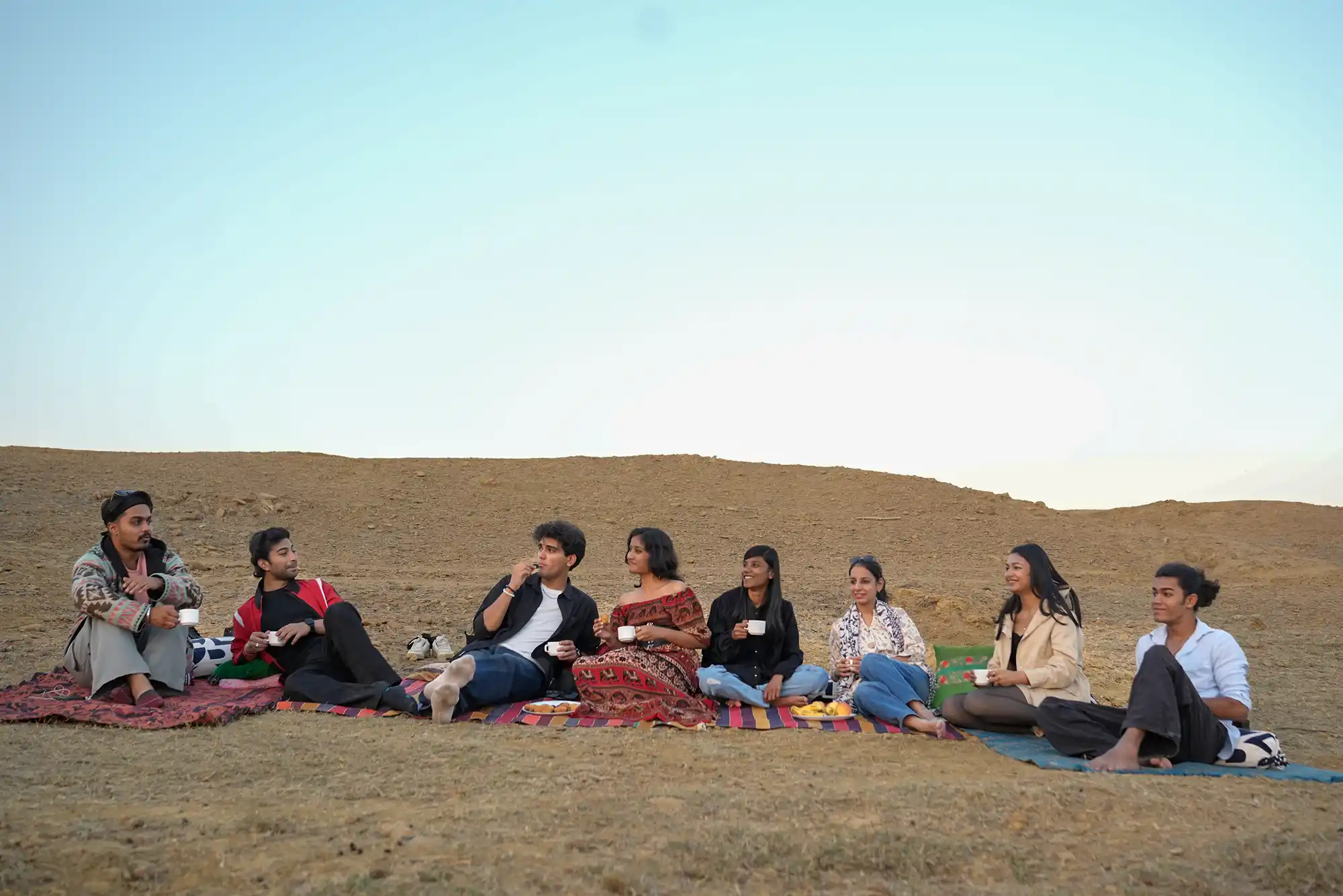 Guests enjoying high tea at a desert oasis near Dreamtime Bungalows, Kuldhara Village, Jaisalmer