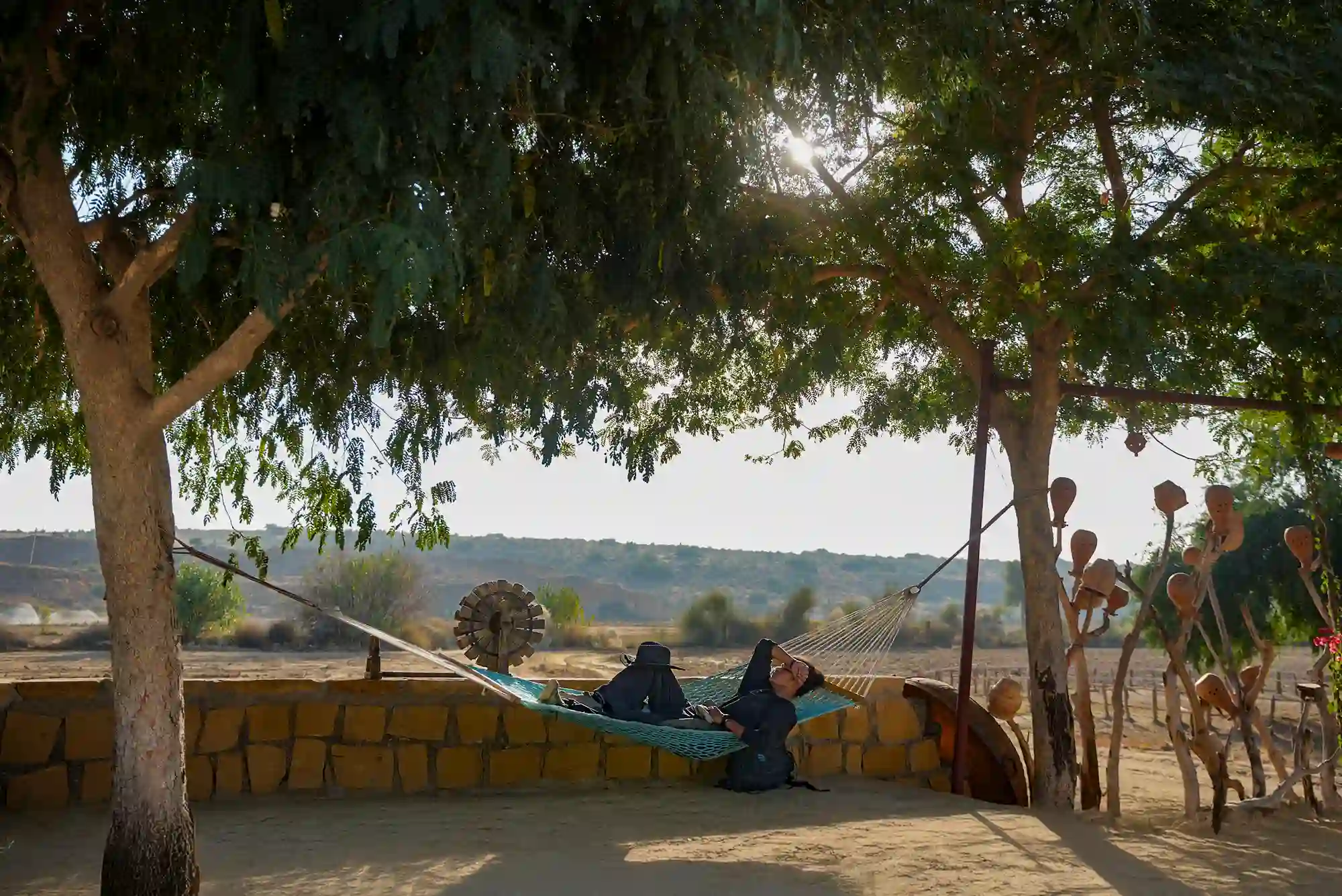 Guest relaxing in a hammock under shaded trees at Dreamtime Bungalows, Rajasthan
